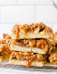 Stacked caramel apple bars drizzled with caramel on a wire rack