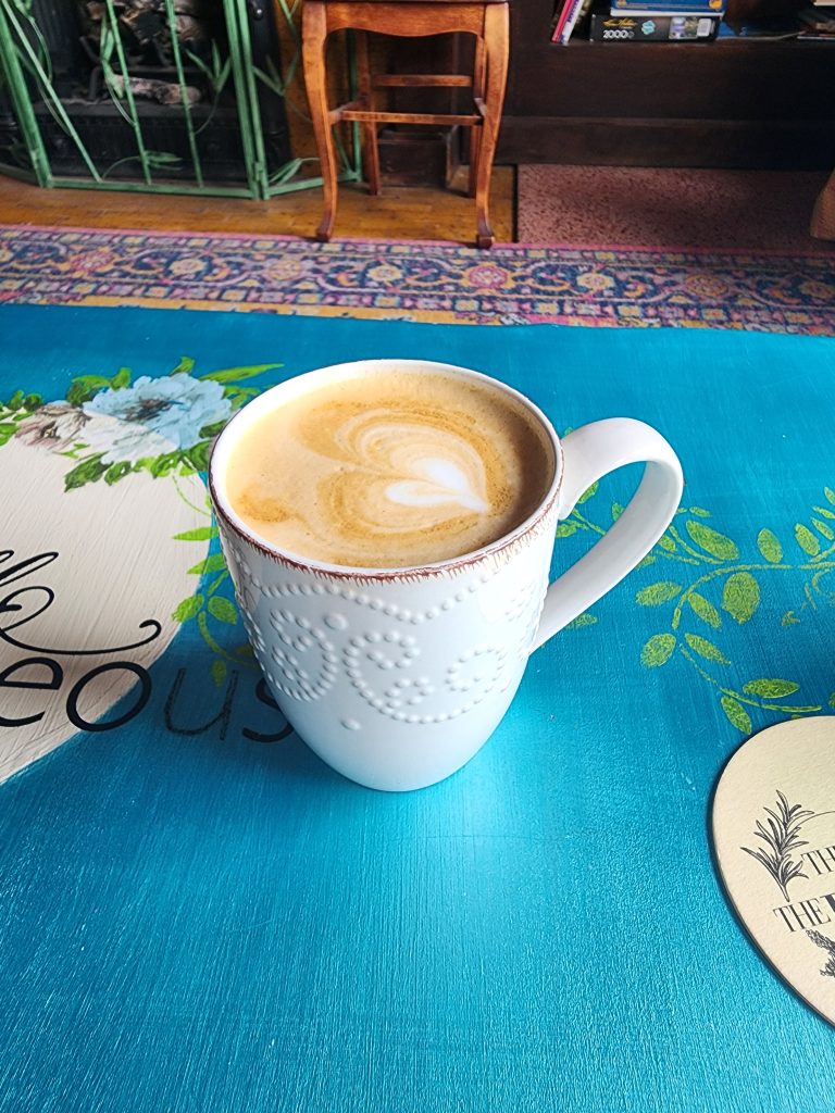 Cup of latte in a white textured mug on a blue table.