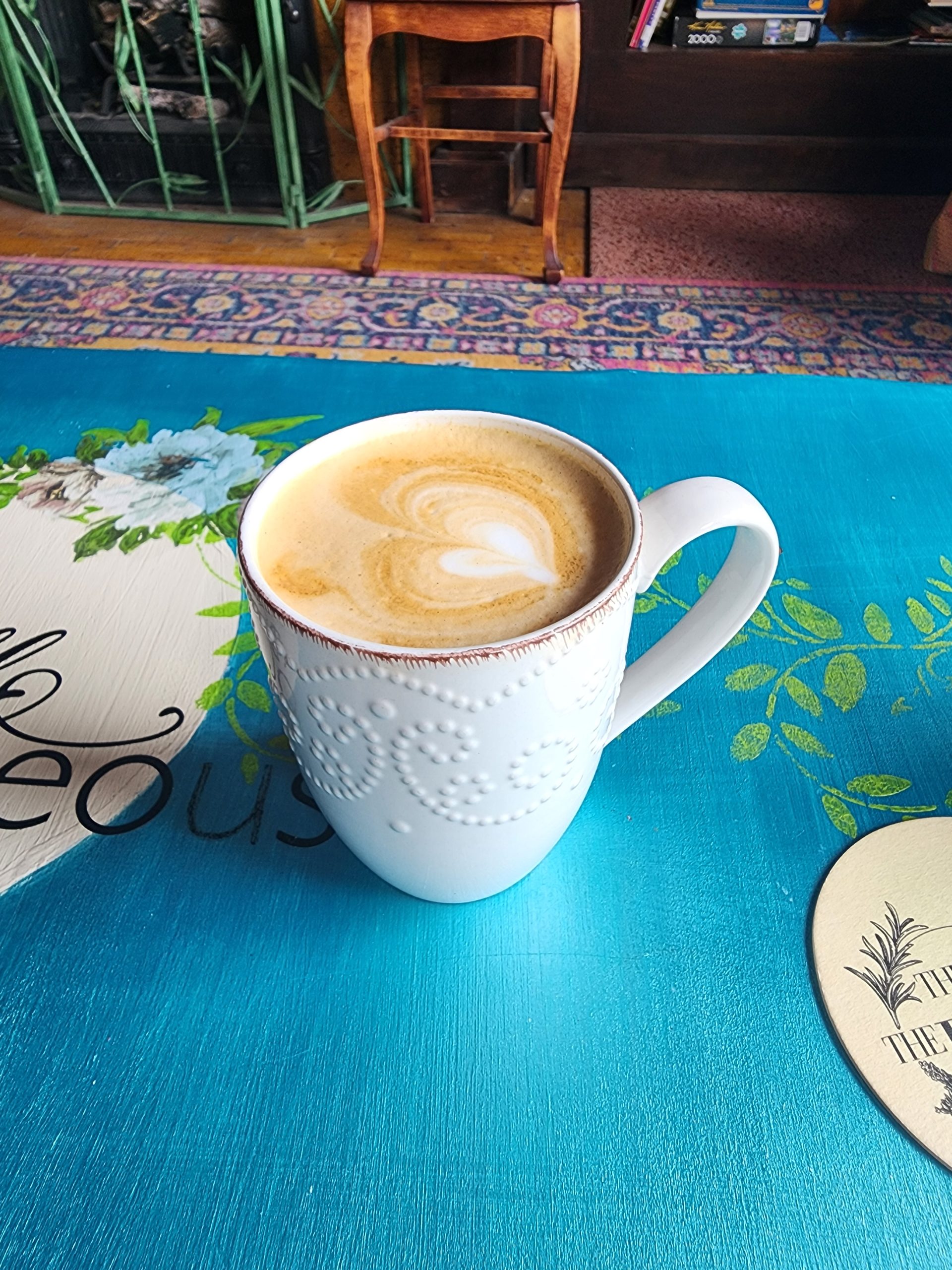 Cup of latte in a white textured mug on a blue table.