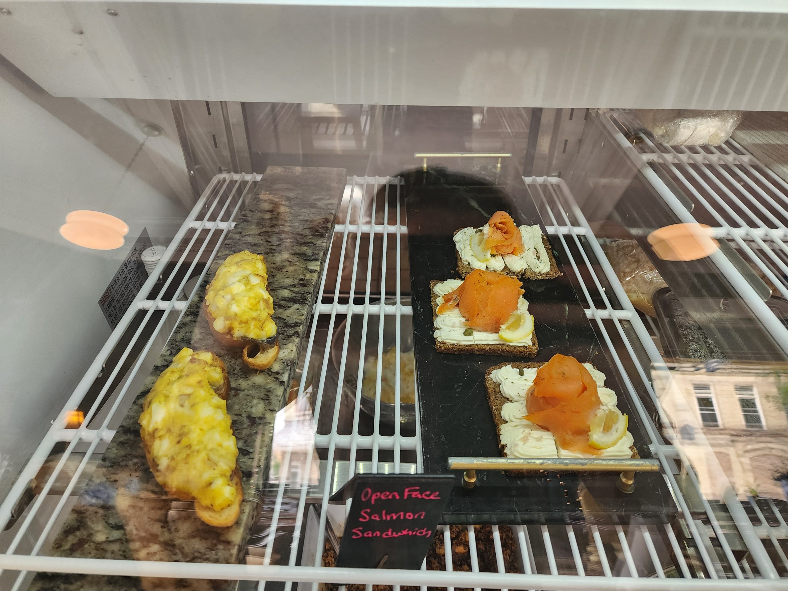 Open-face salmon sandwiches in a display case.
