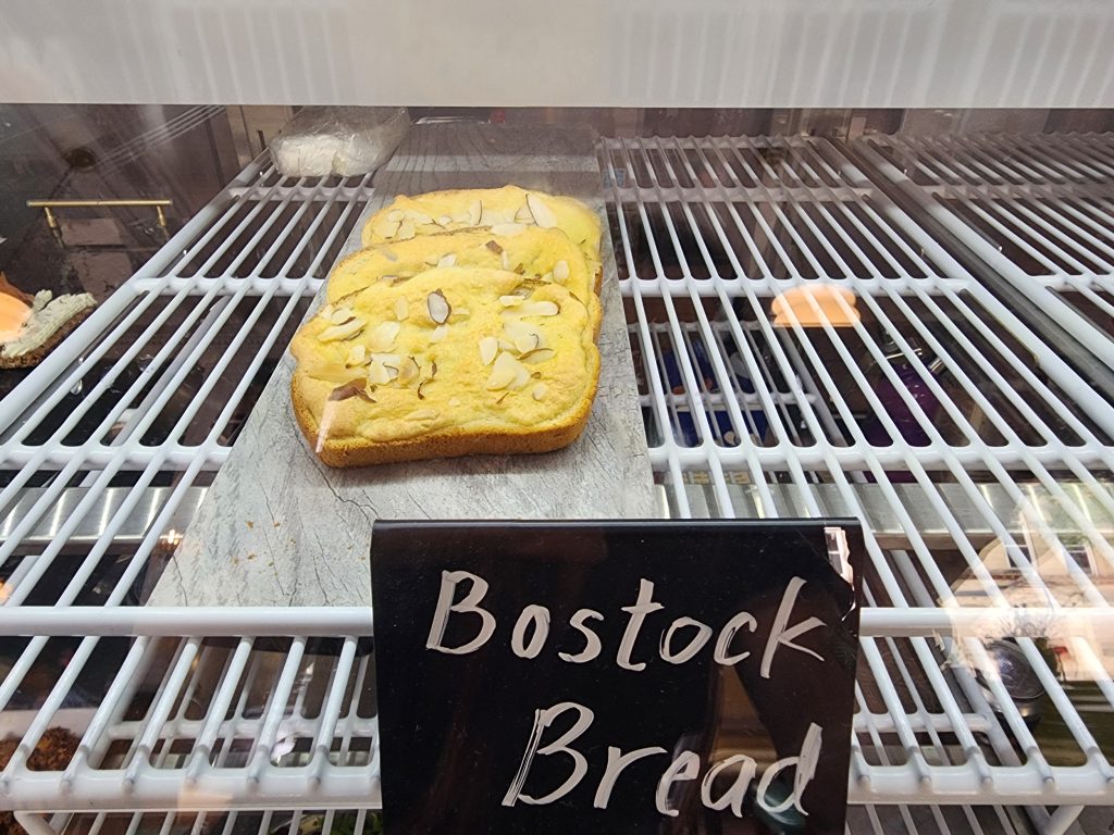 Bostock bread with sliced almonds in a bakery display case.