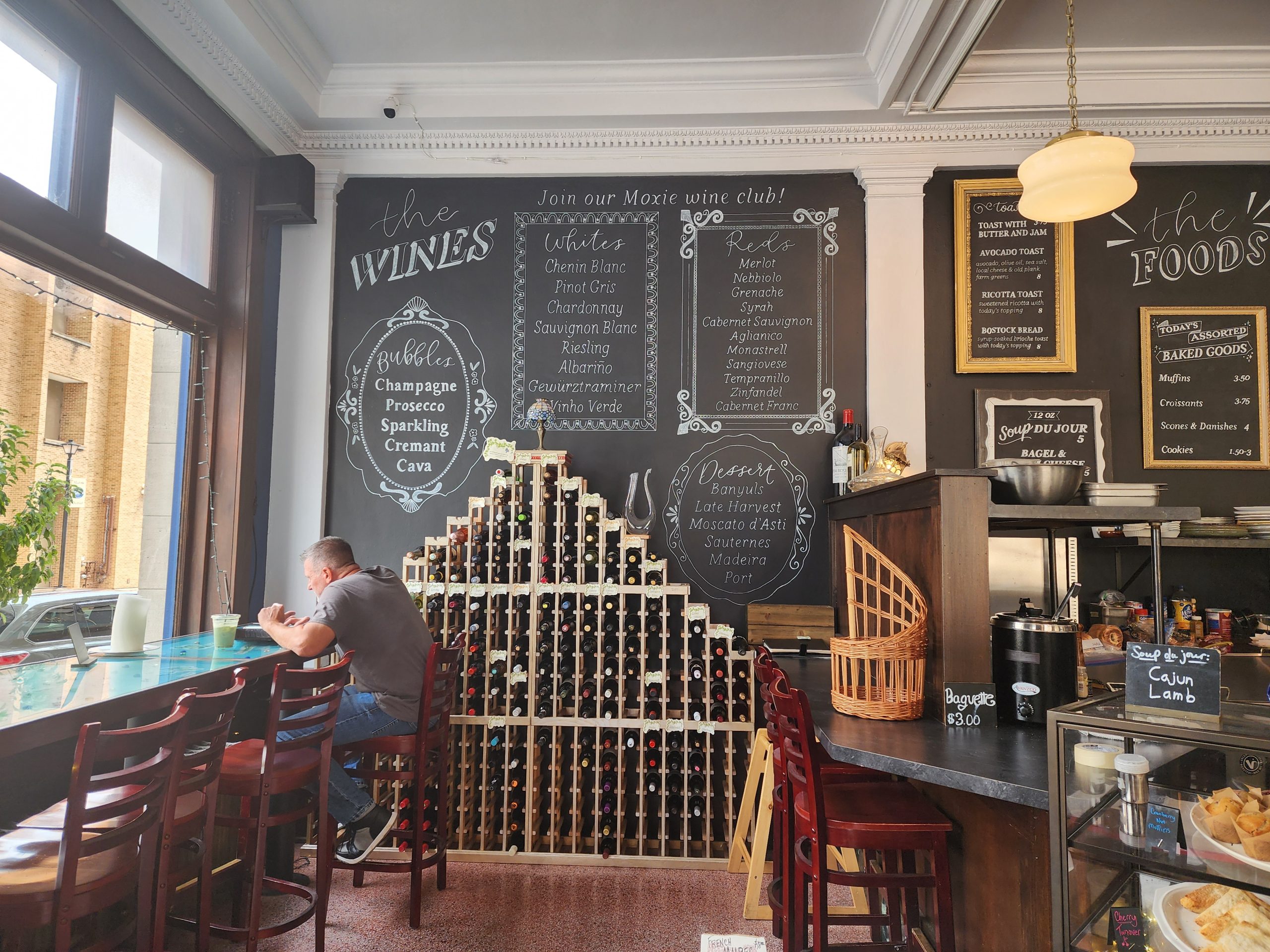 Restaurant interior with a wine display, chalkboard menus, and counter seating.