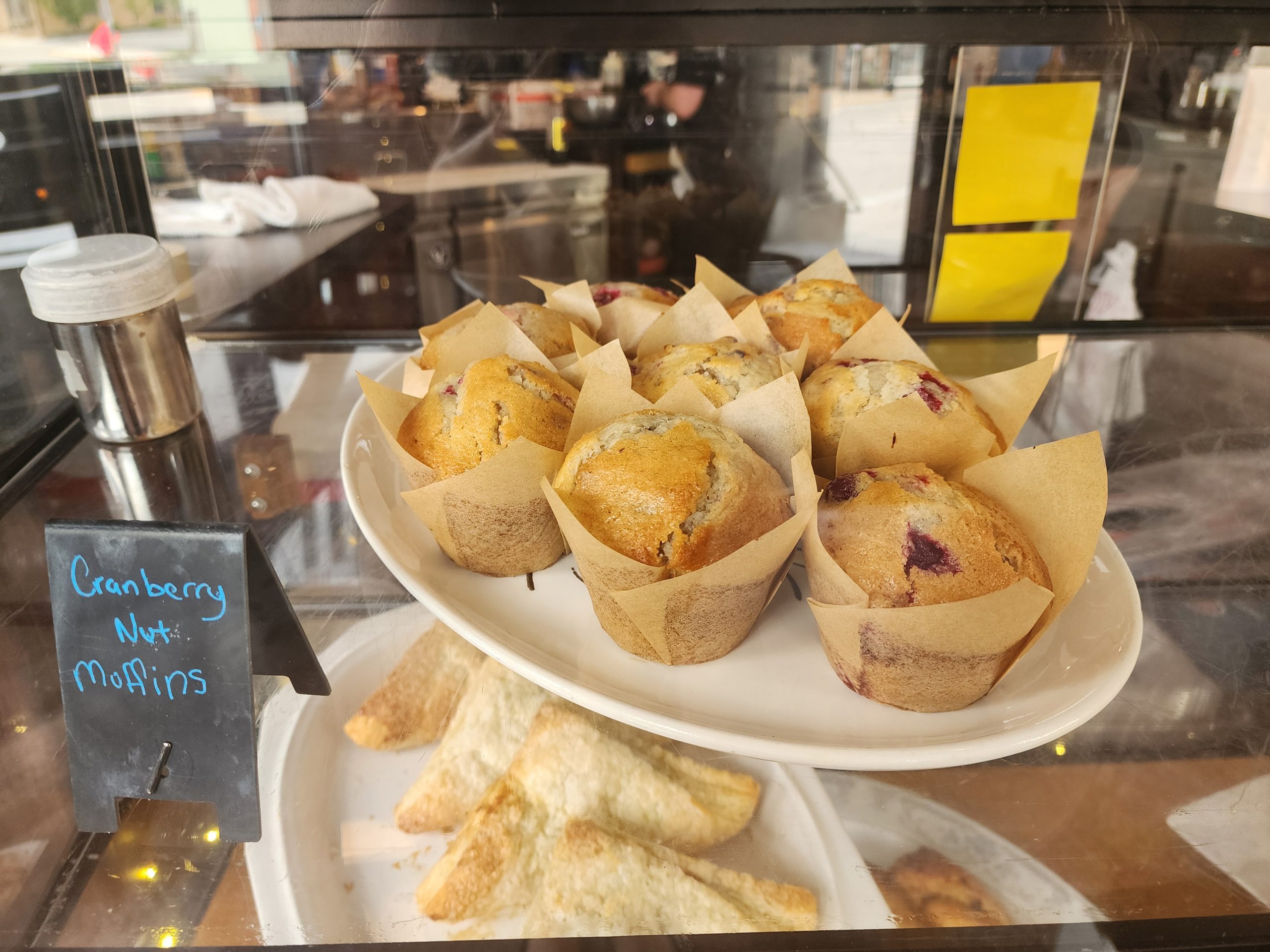 Tray of cranberry nut muffins in a glass bakery case.