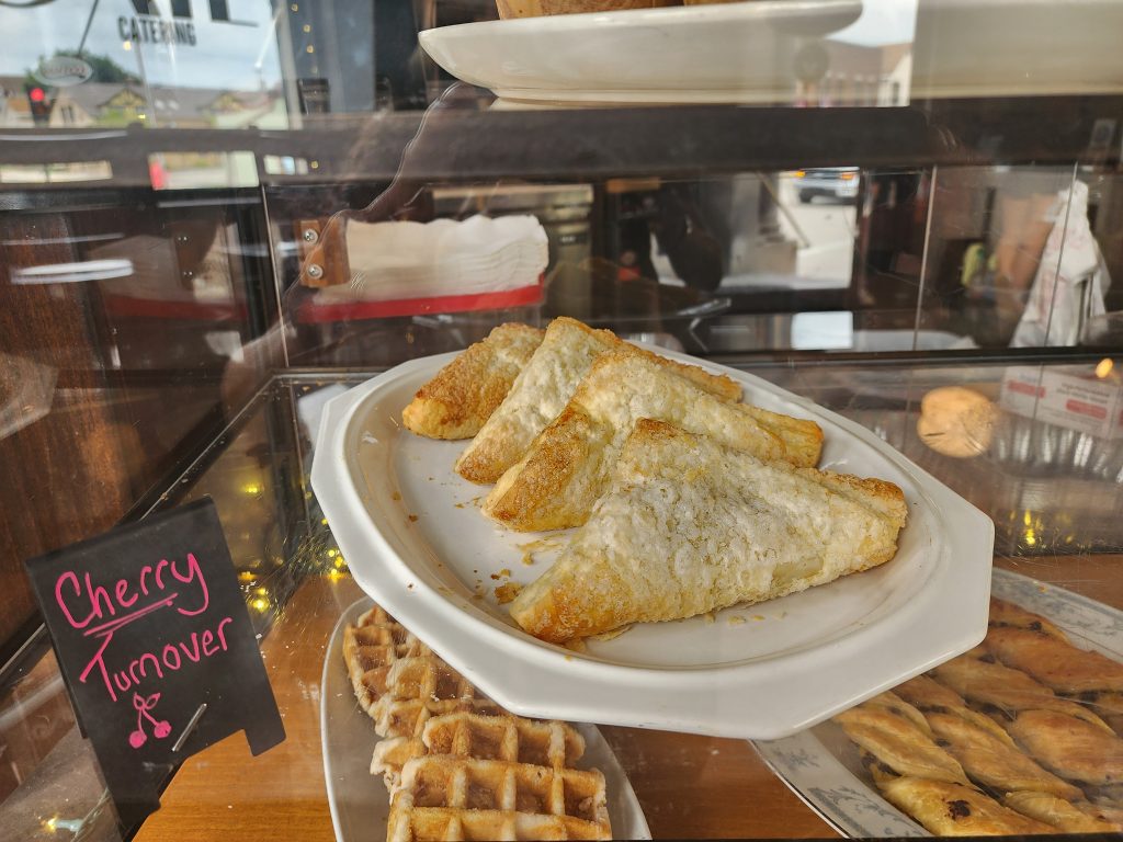 Plate of cherry turnovers in a bakery display case.