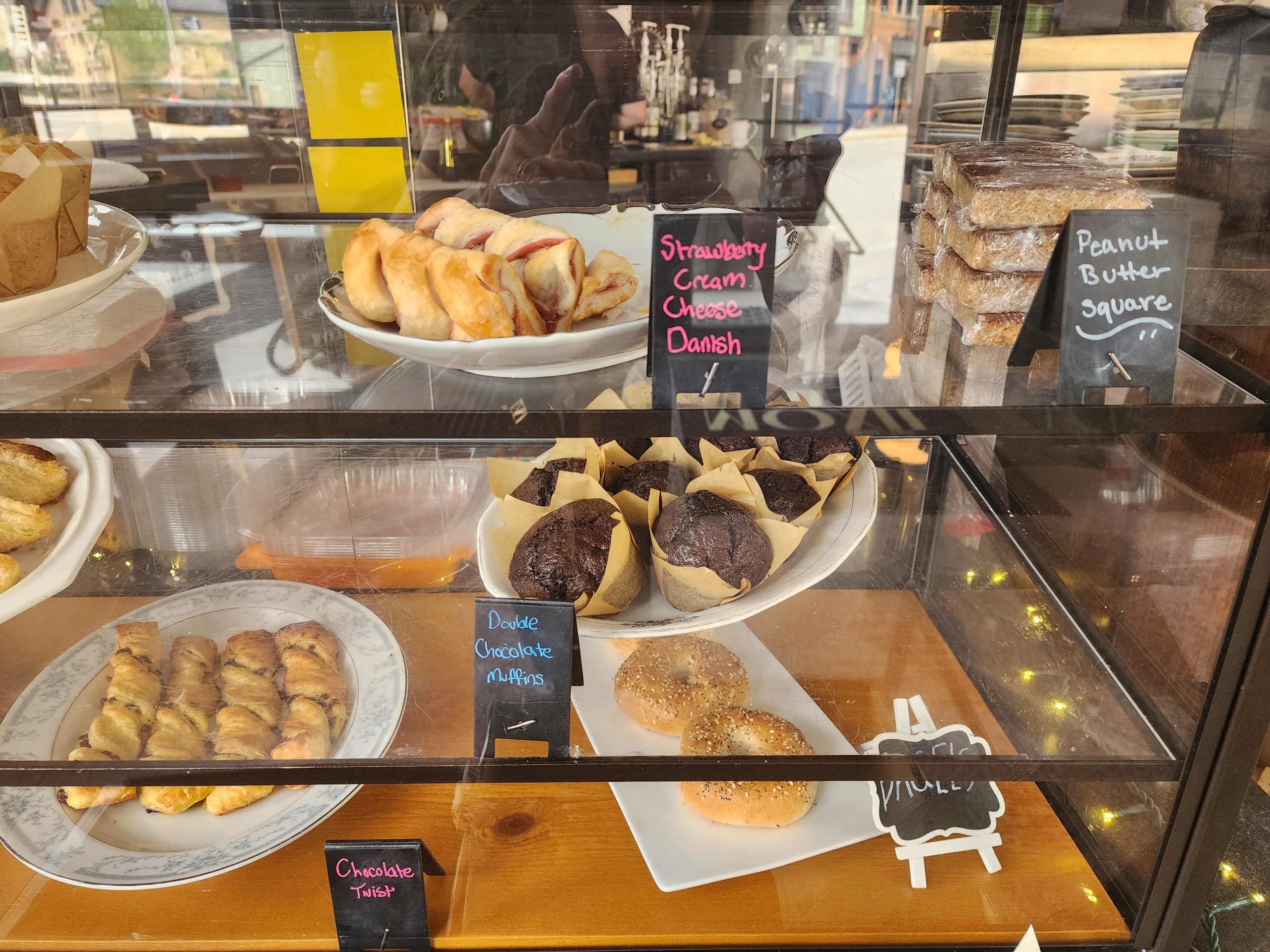 Bakery display case with pastries, muffins, and labeled treats.