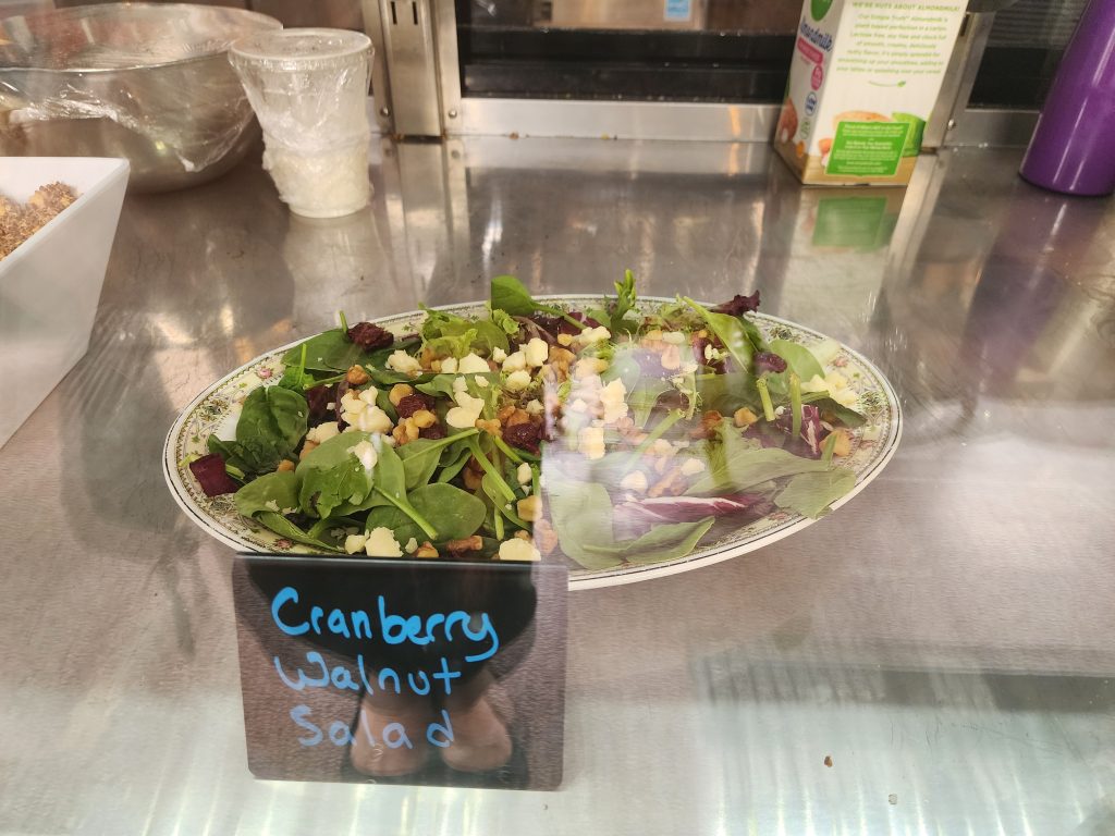 Cranberry walnut salad on a platter behind glass.