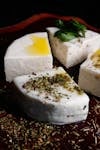 White cheese cubes topped with oil, herbs, and mint leaves.