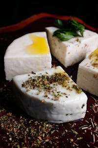 White cheese cubes topped with oil, herbs, and mint leaves.