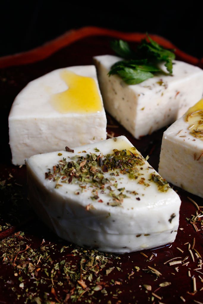 White cheese cubes topped with oil, herbs, and mint leaves.
