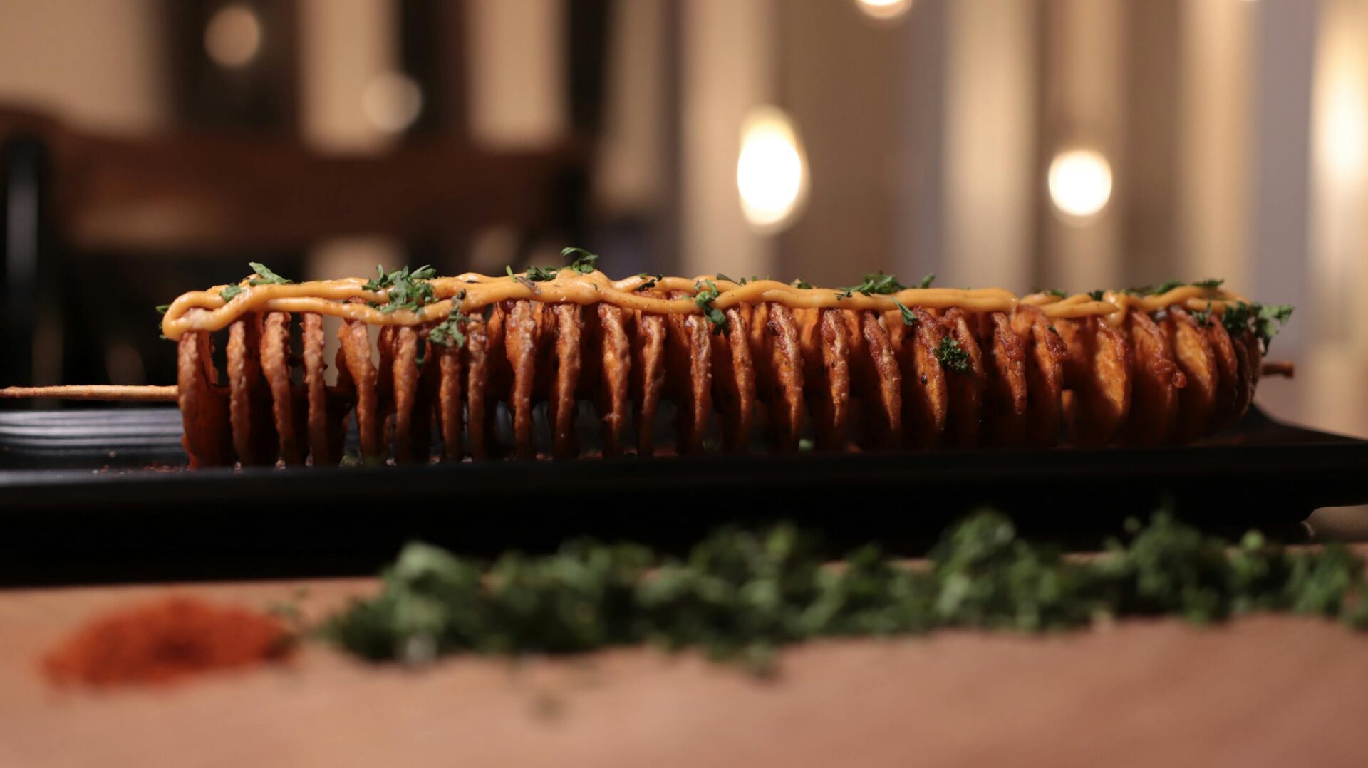 Skewered fried slices topped with sauce and herbs on a serving tray.