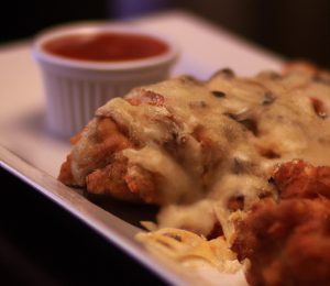Chicken parmesan with melted cheese and marinara sauce on a plate.