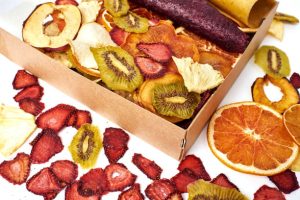 Open craft paper box of mixed dried fruit on a white background.
