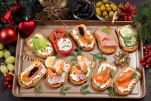 Assorted crostini appetizers with smoked salmon, tomatoes, cucumber, and ham on a festive tray.
