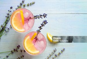 Two glasses of lavender lemonade with lemon slices and ice, viewed from above.