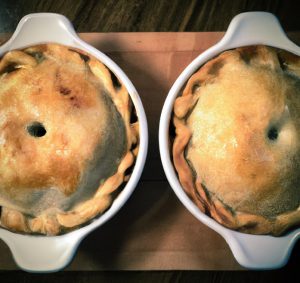 Two baked pot pies in white ceramic dishes.
