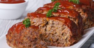 Sliced meatloaf topped with glaze and parsley on a serving platter.