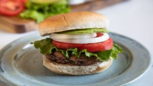 Cheeseburger on a plate with lettuce, tomato, and onion
