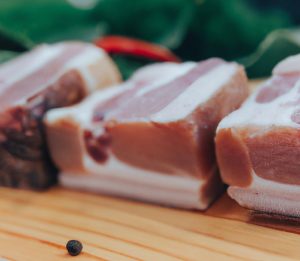 Raw pork pieces on a wooden surface.