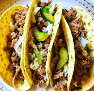 Soft tacos filled with shredded pork, avocado slices, and chopped onion.