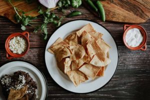 Plate of tortilla chips with small bowls of dip and toppings