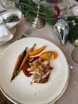 A beautifully plated gourmet dish featuring colorful carrots and tender meat slices on a restaurant table.