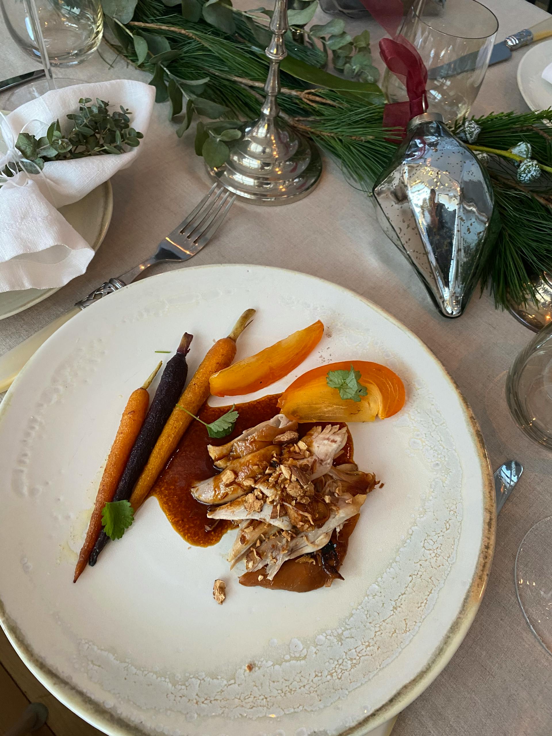 A beautifully plated gourmet dish featuring colorful carrots and tender meat slices on a restaurant table.