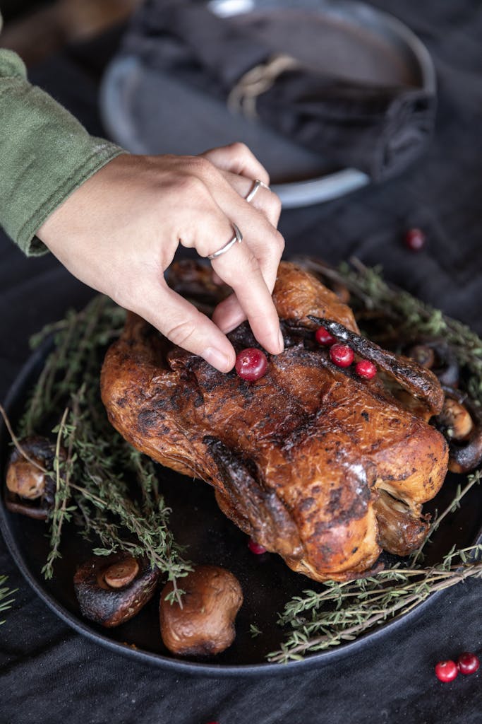A close-up of a roasted turkey being garnished with cranberries, perfect for holiday feasting.