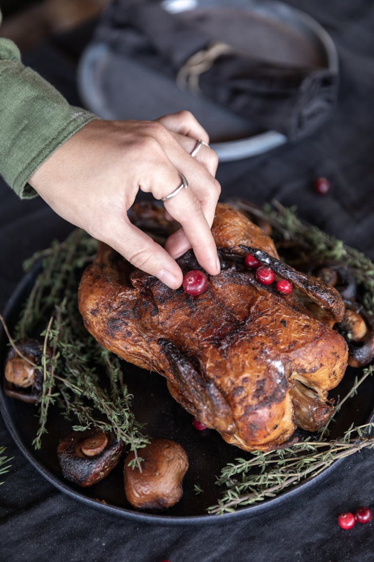 A close-up of a roasted turkey being garnished with cranberries, perfect for holiday feasting.
