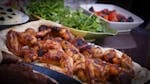 A close-up of grilled chicken wings served with fresh herbs and vegetables, perfect for culinary presentations.
