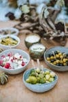 A diverse selection of fresh Mediterranean appetizers presented in ceramic bowls on a rustic wooden table.