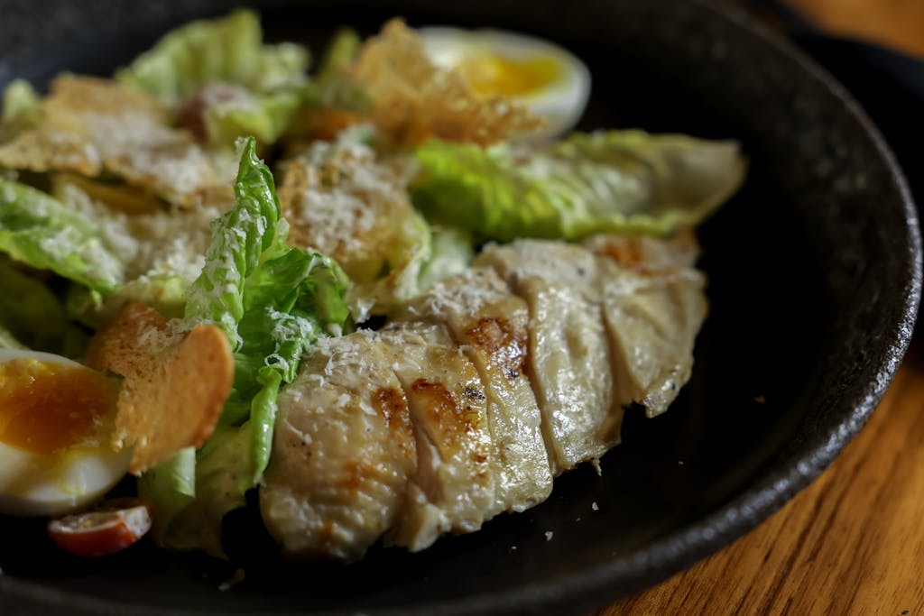 A flavorful Caesar salad topped with grilled chicken and hard-boiled eggs.