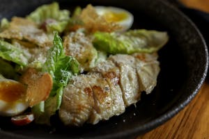 A flavorful Caesar salad topped with grilled chicken and hard-boiled eggs.