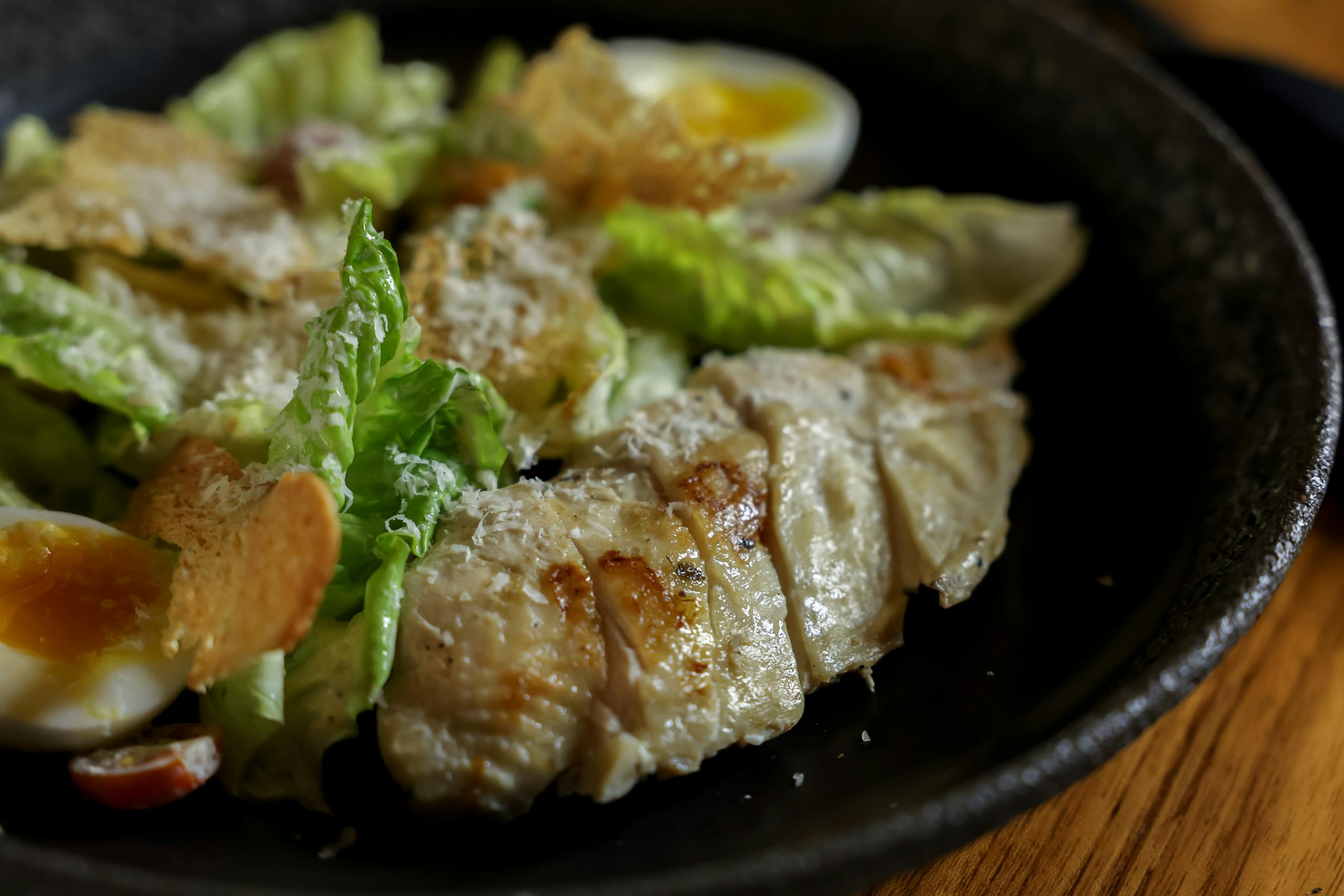 A flavorful Caesar salad topped with grilled chicken and hard-boiled eggs.