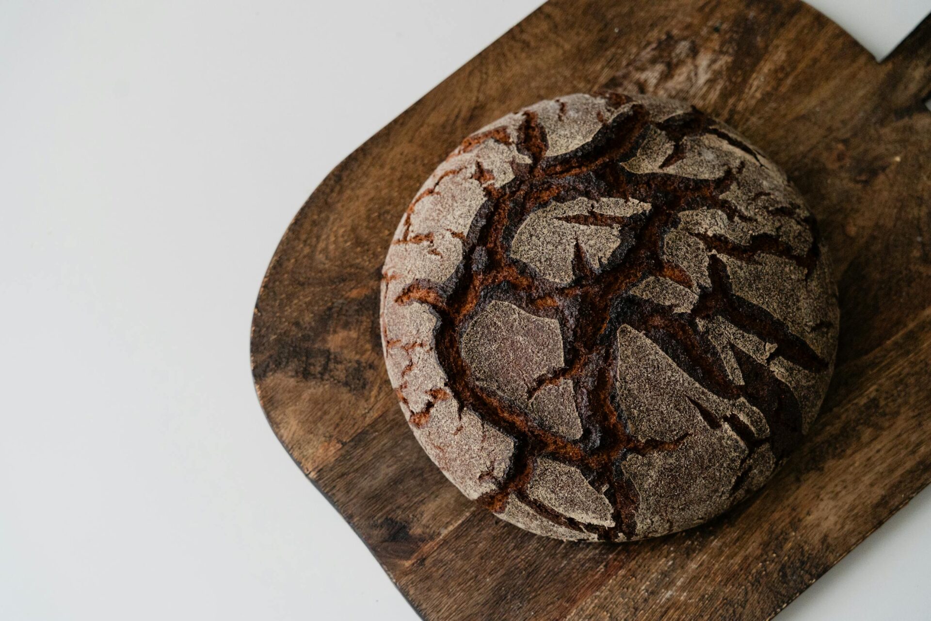 A high-angle view of a rustic round loaf of artisan bread on a wooden cutting board.