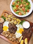 A mouth-watering display of steak with salad, eggs, and mushrooms on a wooden board.
