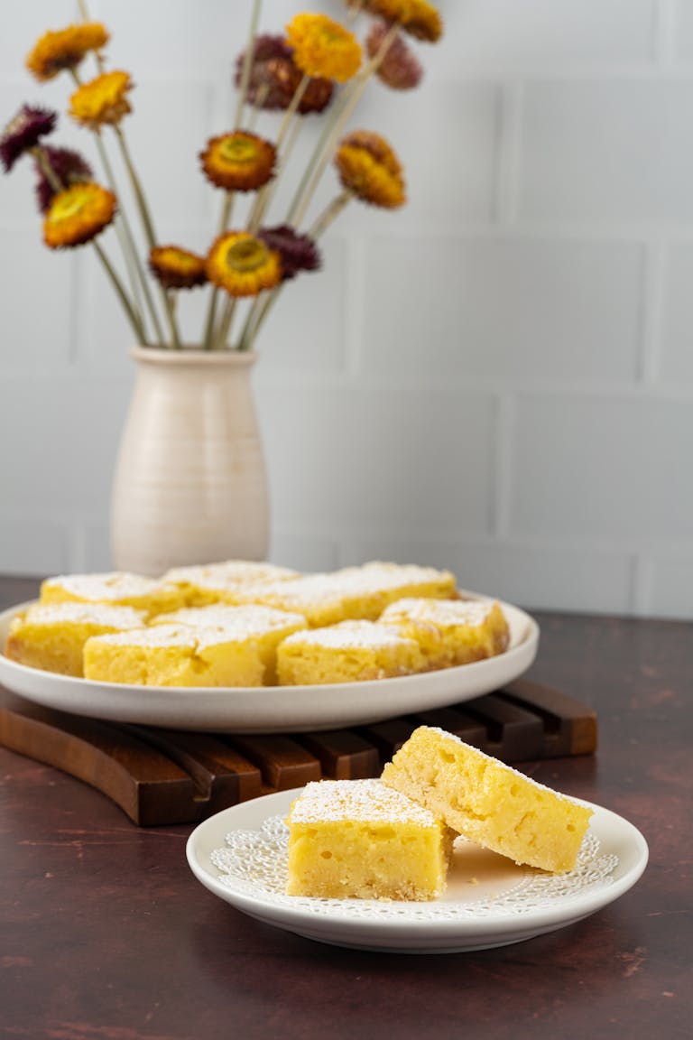 A plate of cornbread slices with a vase of flowers in a cozy setting.