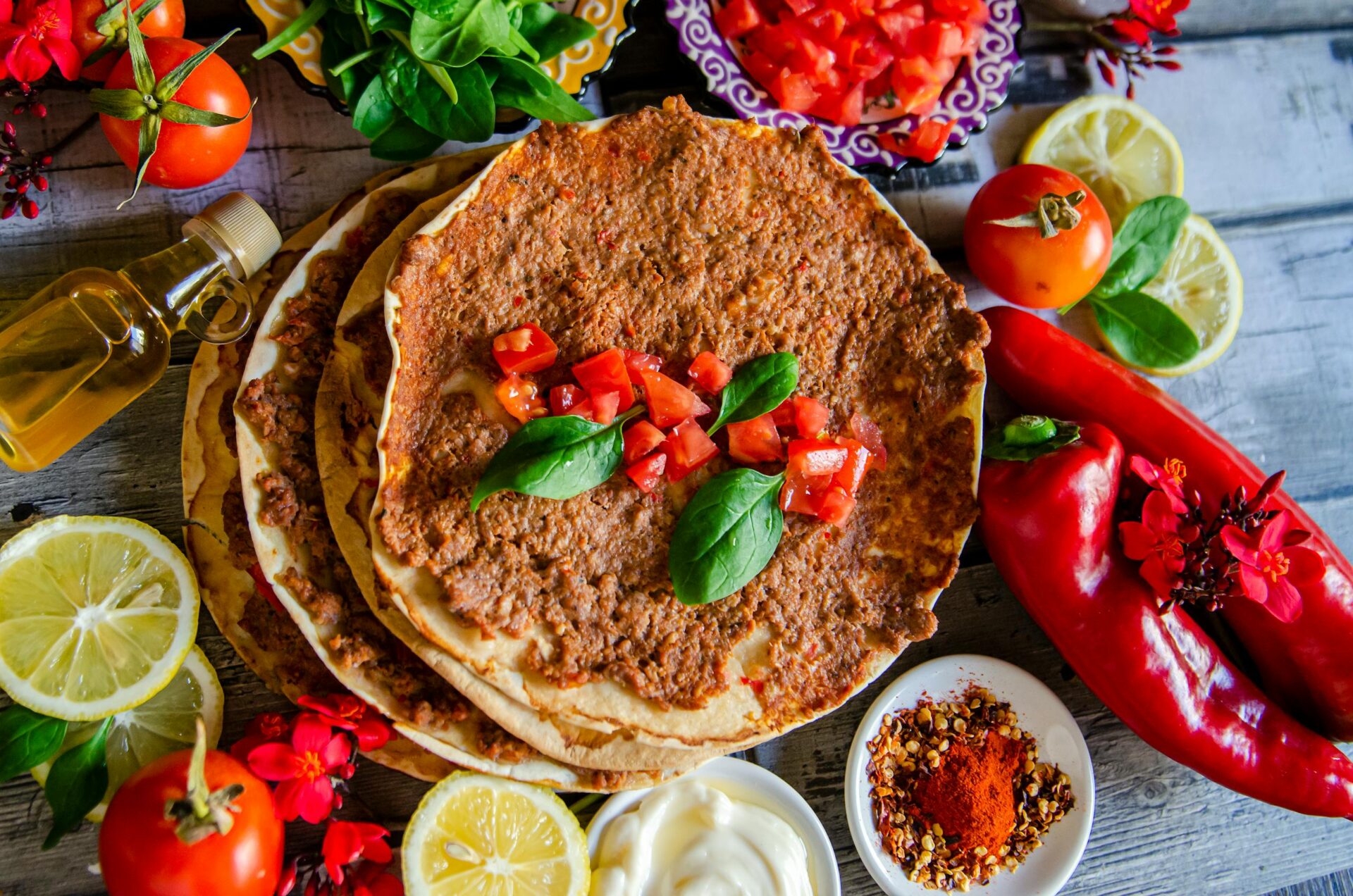 A top-down view of delicious homemade Turkish lahmacun garnished with fresh basil and vibrant ingredients.