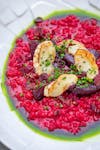A vibrant beetroot risotto with grilled cheese and fresh herbs, perfect for a gourmet meal.