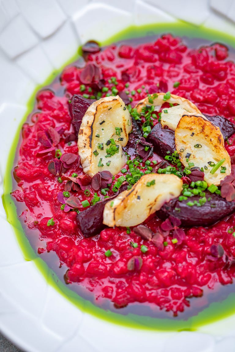 A vibrant beetroot risotto with grilled cheese and fresh herbs, perfect for a gourmet meal.