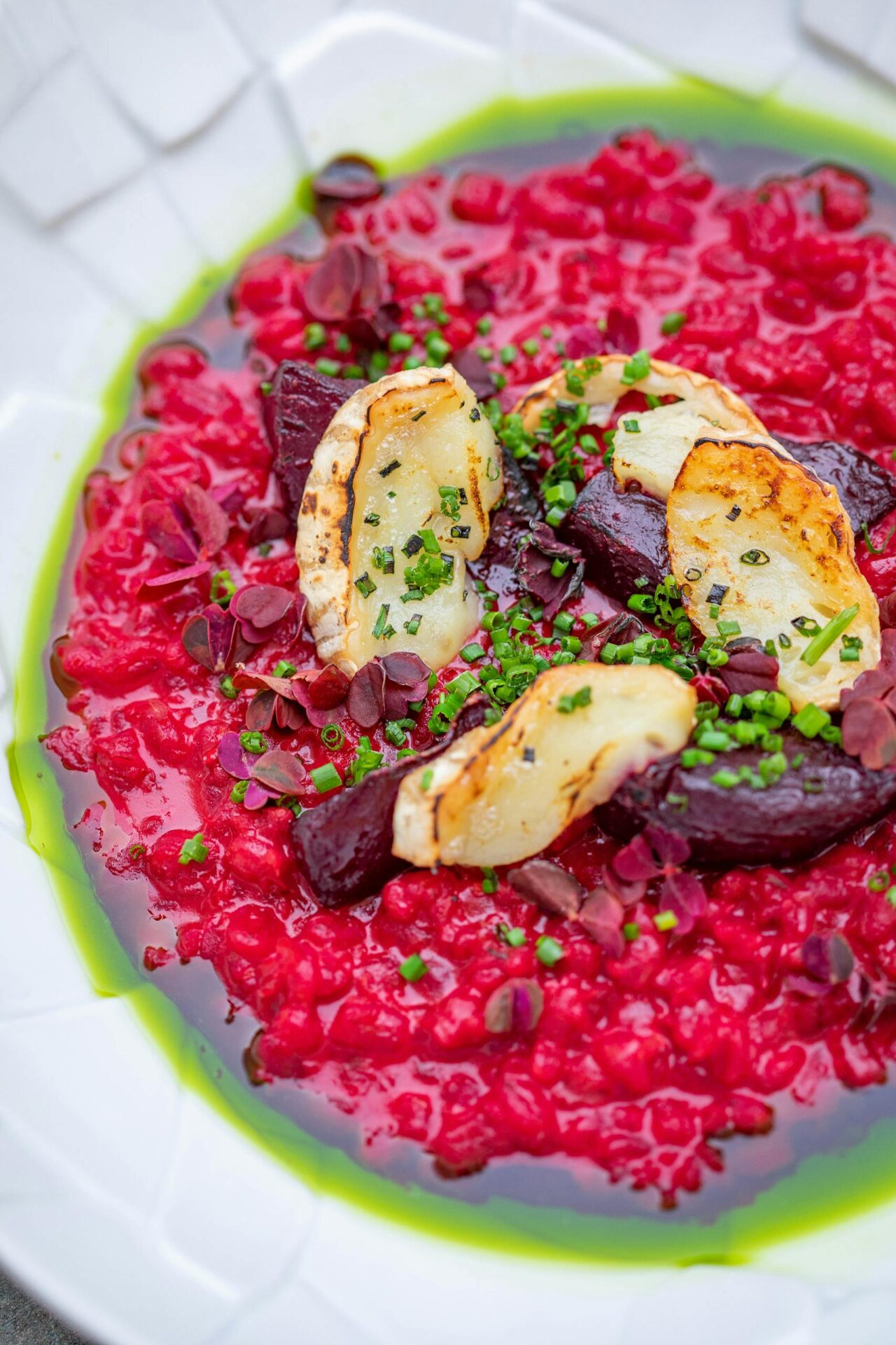 A vibrant beetroot risotto with grilled cheese and fresh herbs, perfect for a gourmet meal.