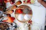 A vibrant flat lay of spices, vegetables, and kitchen tools on a wooden chopping board.