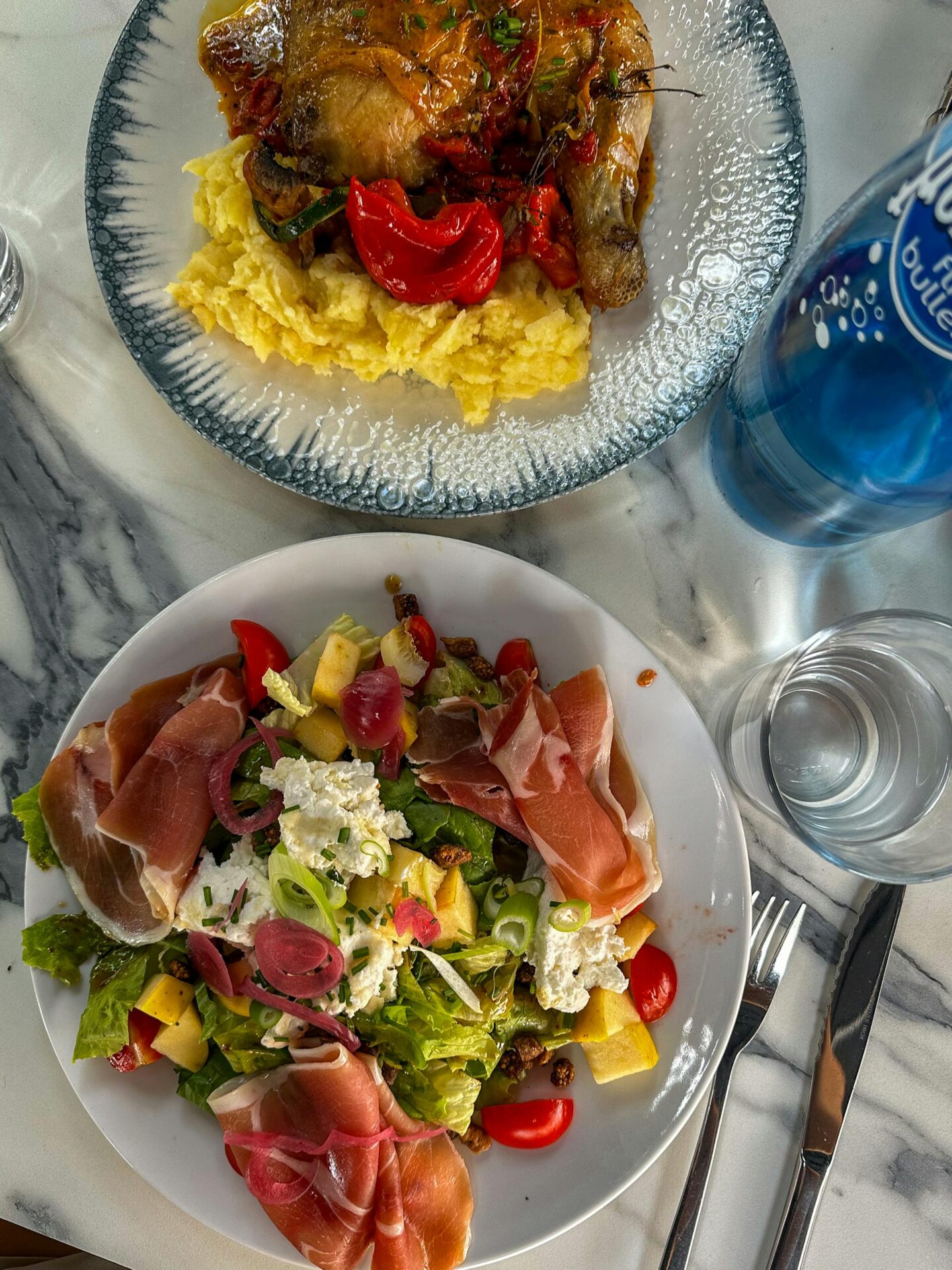 A vibrant plate of fresh salad and roasted chicken with mashed potatoes at a French bistro table in Arles.