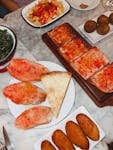 A vibrant spread of Spanish tapas including patatas bravas, bread with tomato, and croquettes on a marble table.