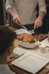 A warm indoor setting featuring a holiday dinner with roast turkey being served, surrounded by family.