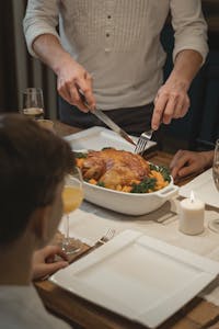 A warm indoor setting featuring a holiday dinner with roast turkey being served, surrounded by family.