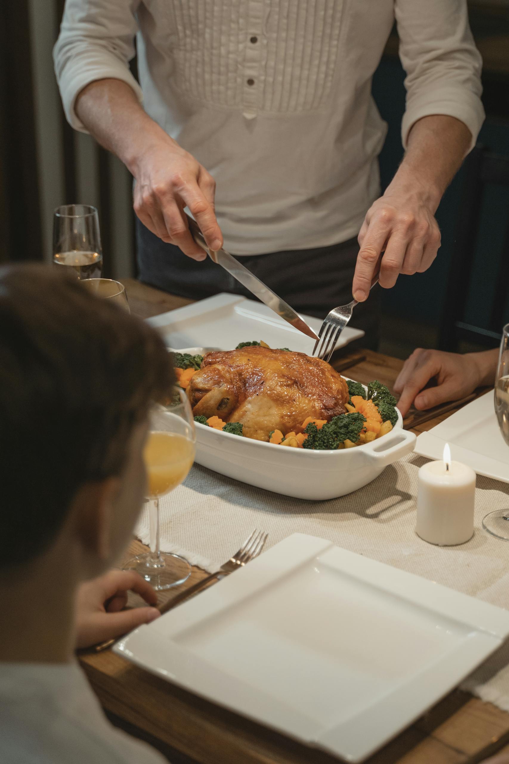 A warm indoor setting featuring a holiday dinner with roast turkey being served, surrounded by family.