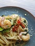 Appetizing shrimp pasta garnished with fresh chili and herbs in a close-up view.