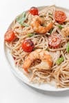 Appetizing shrimp spaghetti with cherry tomatoes served on a white plate.