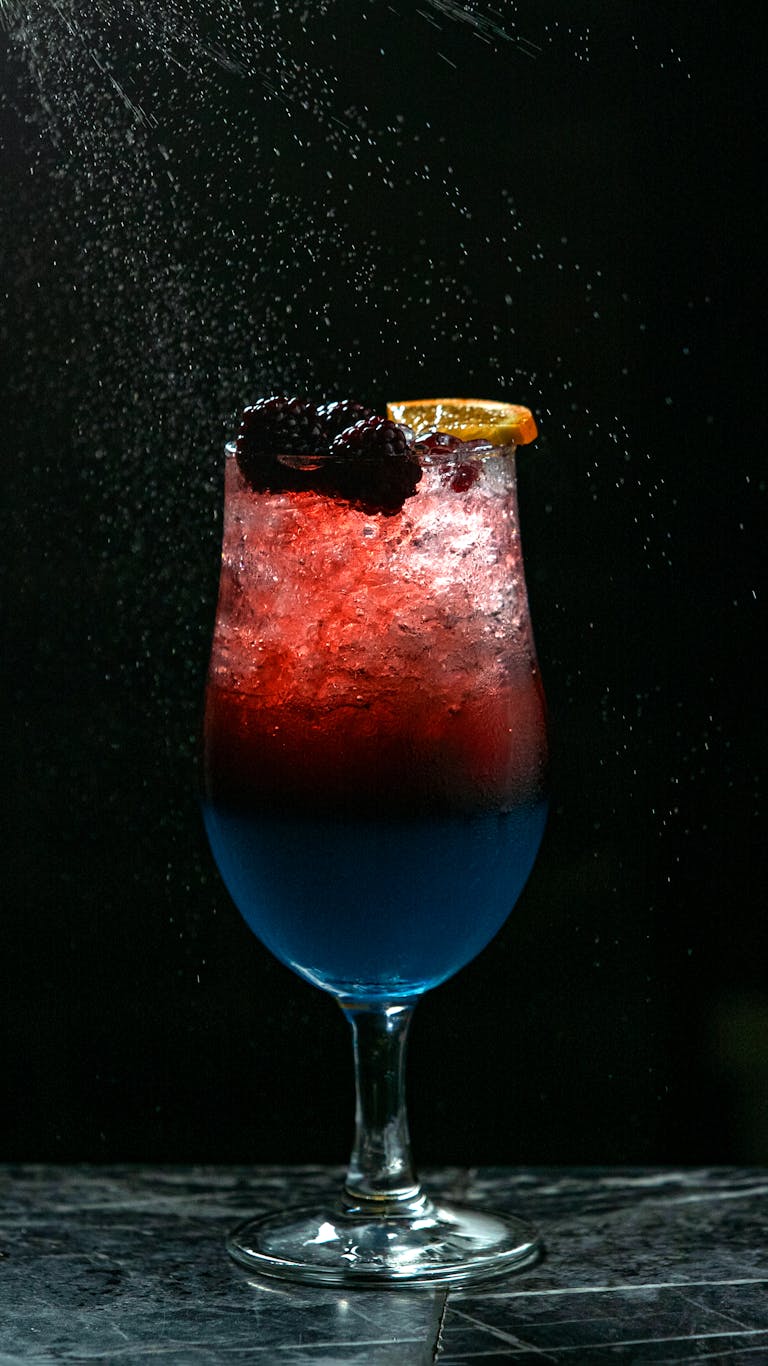 Artistic shot of a vibrant berry and citrus cocktail with dark background.