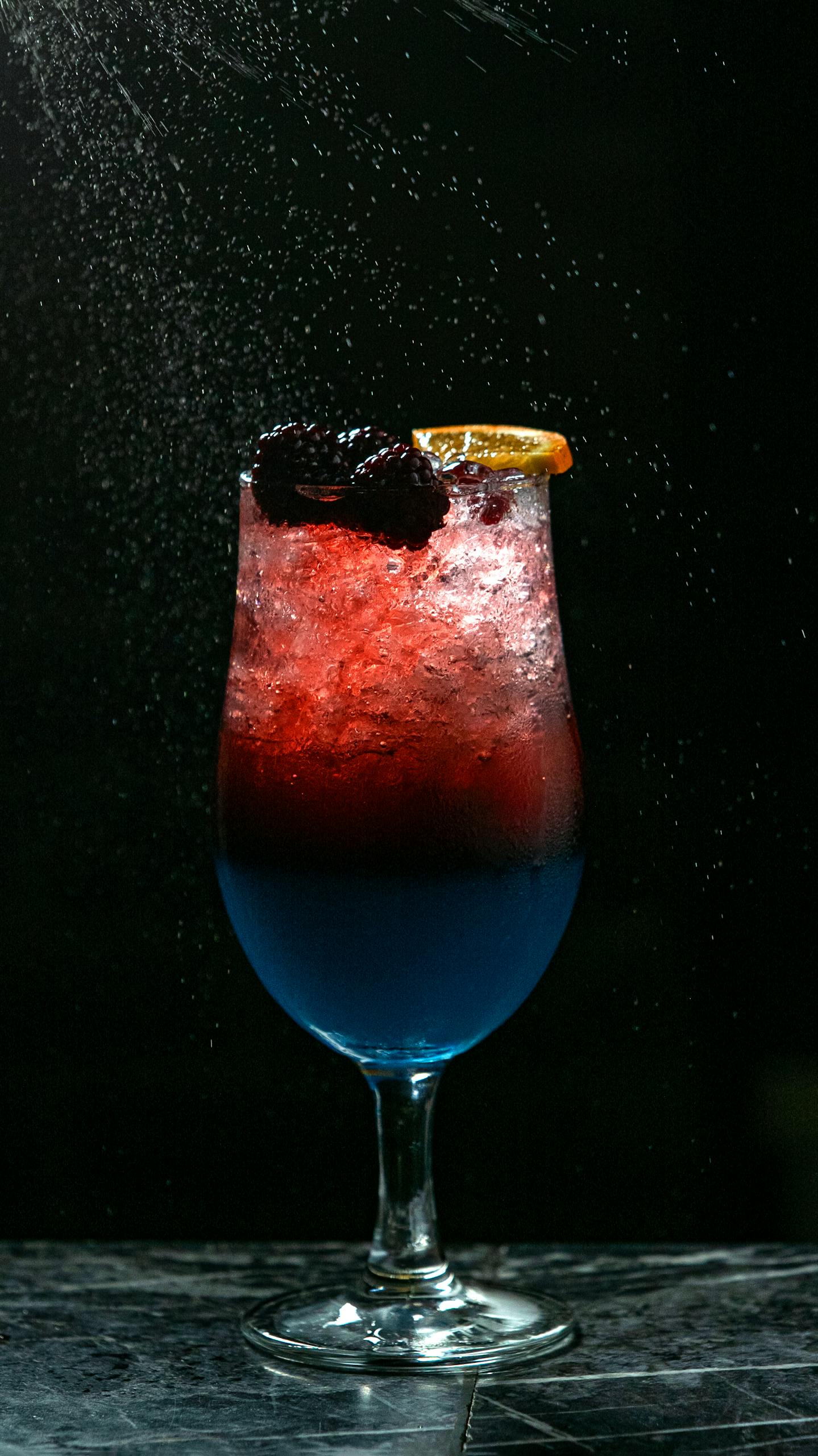 Artistic shot of a vibrant berry and citrus cocktail with dark background.